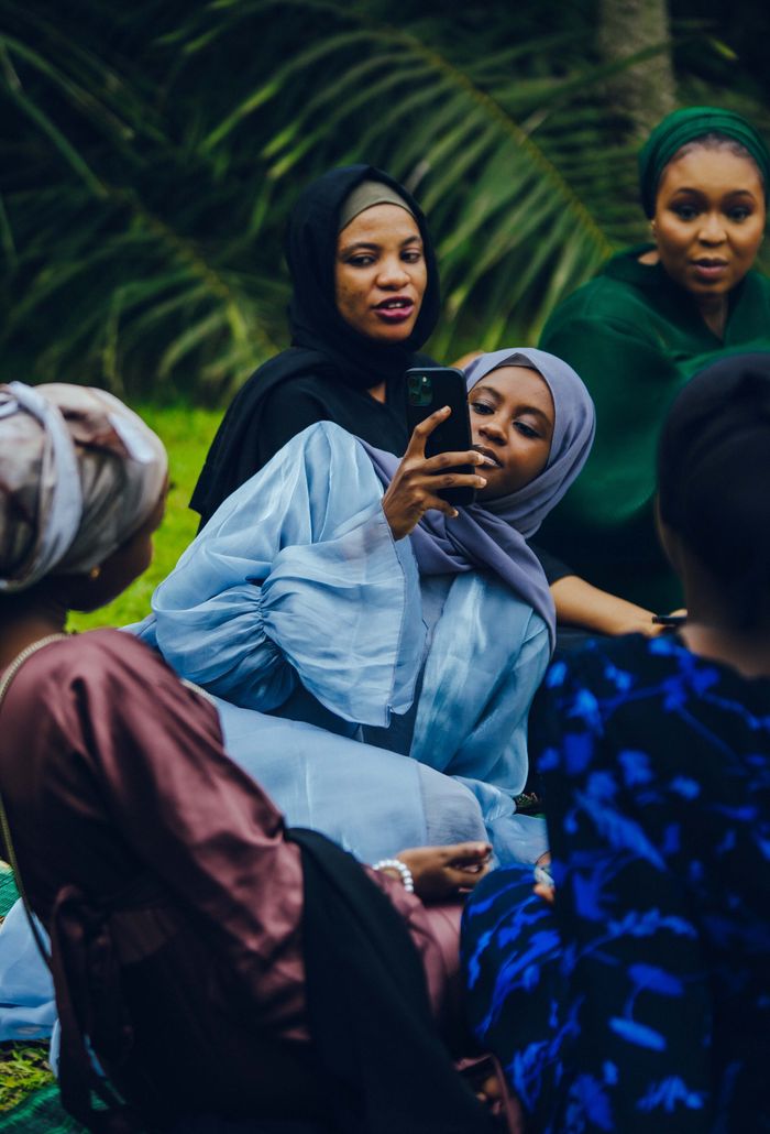 Group of diverse women in hijabs capturing moments outdoors in Nigeria.