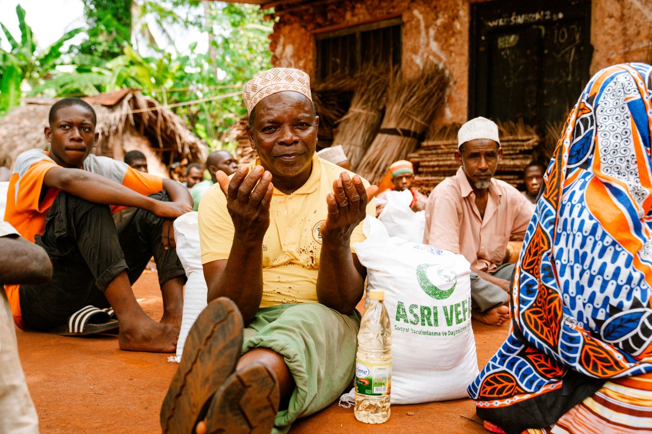 A group of people in a rural setting engaged in communal activities and conversation.